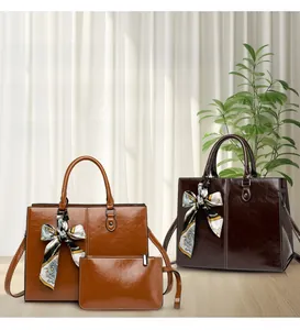Detail of oil wax leather tote bag and pouch set with decorative silk scarf handle