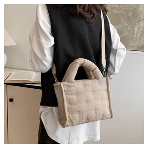 Details der beige gesteppten Daunentasche mit verstellbarem Gurt und Stickereidetails