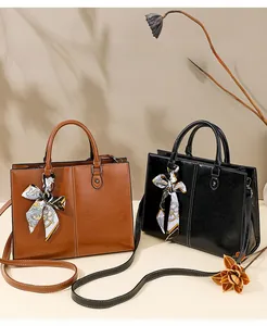 Detail of oil wax leather tote bags in brown and black with silk scarf and white stitching