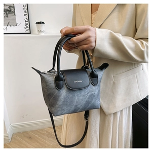 Détail du sac à main en denim gris avec poignée en cuir noir et logo ZHCNMA