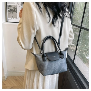 Détail d'un sac à bandoulière en denim gris avec rabat en cuir noir et lettrage ZHONMA