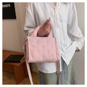 Detailansicht einer rosa gesteppten Umhängetasche an einem Model in minimalistischem Stil
