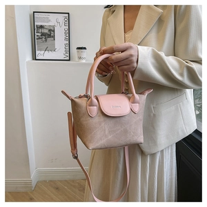 Sac seau beige chic avec bordure en cuir rose présenté dans un cadre élégant