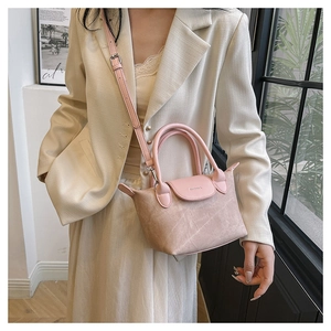 Détail du sac seau beige et rose avec texture en daim et finitions métalliques argentées