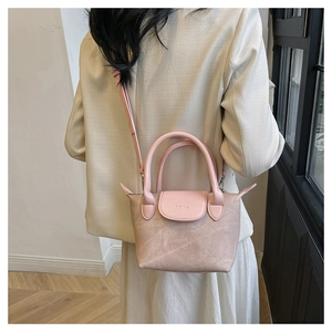 Petit sac seau rose en similicuir texturé avec bandoulière porté par un mannequin