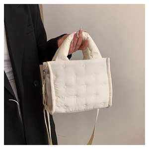 Detailansicht der cremefarbenen gesteppten Daunentasche mit Rundnaht und Crossbody-Gurt