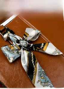 Detail of dark brown oil wax leather bag with a vintage patterned silk scarf bow
