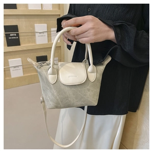 Détail du sac seau mat vert clair avec bordure en cuir crème et poignée supérieure à la main