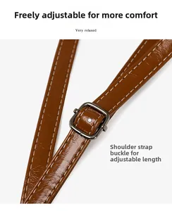 Detail of adjustable oil wax leather shoulder strap with dark gray metal buckle and stitching