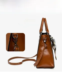 Detail of vintage brown leather handbag featuring detachable bronze hook and silk scarf