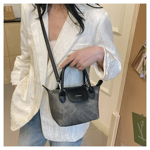 Détail du petit sac seau gris avec rabat en cuir noir et lettrage argenté sur modèle