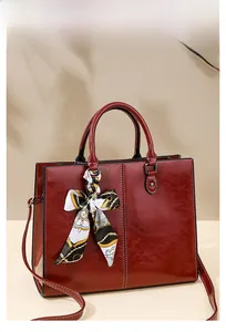 Detail of burgundy oil wax leather handbag featuring decorative patterned silk scarf