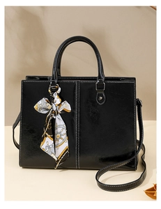 Detail of black wax leather tote bag with contrast stitching and decorative silk scarf