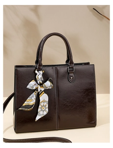 Detail of dark brown oil wax leather handbag with stylish printed silk scarf and shoulder strap