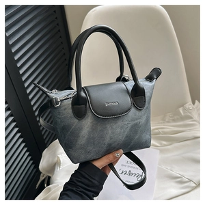 Détail du petit sac seau en denim délavé gris avec finitions et anses en cuir noir