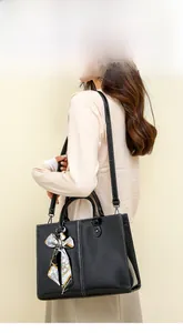 Detail of black wax leather tote bag with white stitching and decorative handle scarf
