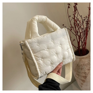 Detailaufnahme einer gesteppten Daunenhandtasche mit dicken Griffen und Web-Schultergurt