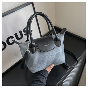 Détail d'un sac bandoulière en denim gris avec rabat en cuir noir et boucles argent