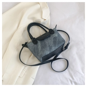 Détail d'un petit sac seau en denim bleu clair avec garniture et poignée en cuir noir