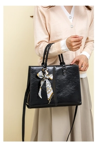 Close-up of black waxed leather tote with contrast white stitching and decorative silk scarf