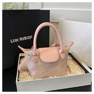 Détail du mini sac seau en toile beige avec poignée en cuir rose et logo embossé