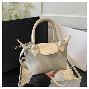 Détail du sac seau en toile grise avec poignée en cuir blanc et logo ZHCNMA