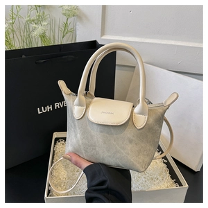 Détail d'un mini sac seau en toile grise avec des finitions en cuir de couleur crème