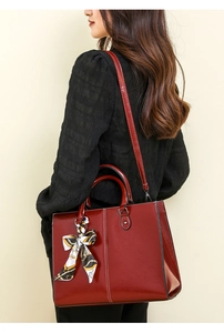 Detail of burgundy wax leather tote with decorative silk scarf and white stitching