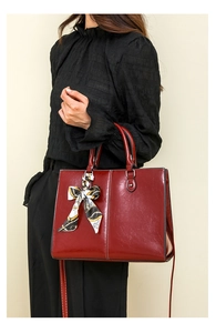 Detail of red oil wax leather tote bag featuring a decorative silk scarf and adjustable strap