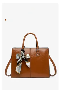 Close-up of brown oil-wax leather tote bag featuring contrast stitching and a silk scarf