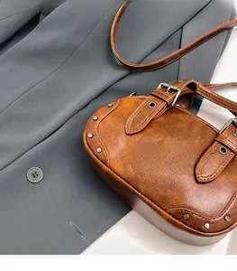 Close-up of vintage brown leather bowling bag featuring silver studs and buckle details