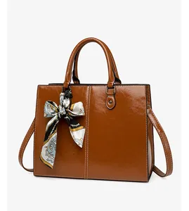 Brown oil wax leather tote bag detail with contrast stitching and decorative scarf