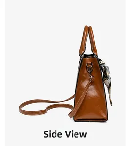 Detailed side view of brown glossy oil wax leather handbag with decorative floral scarf