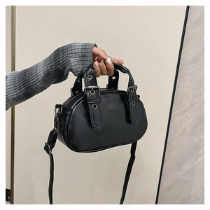 Detail of black bowling bag with rivets, shiny finish and adjustable strap handles