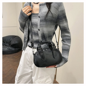Close-up of a vintage black leather bowling bag with silver studs on a female model