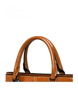 Close-up of brown oiled leather bag handle with white stitching and silver hardware