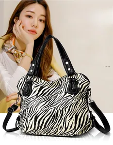 Detail view of large zebra print tote bag featuring black leather handles and silver hardware