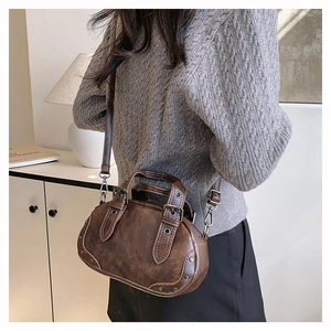 Detailed view of vintage dark brown bowler bag featuring silver studs and buckle straps