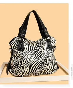 Macro detail of zebra print leather tote bag with silver rivets and black handles