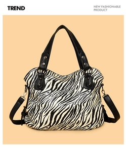Detail of zebra print tote bag featuring black handles and adjustable metal hardware