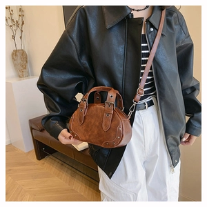 Close-up of vintage brown leather mini bowling bag with metallic rivets and buckles