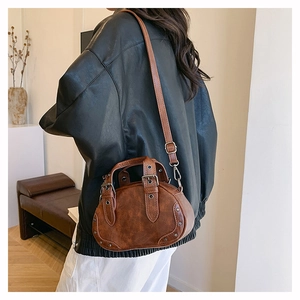 Retro caramel brown bowling bag with silver studs and adjustable shoulder strap worn by model