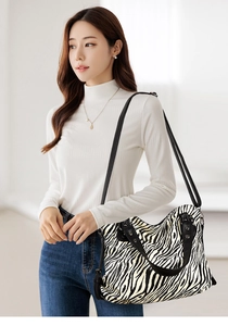 Model wearing a large zebra print tote bag with black handles and silver hardware detail