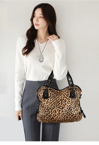 Detail of leopard print tote bag with black leather straps on model's shoulder