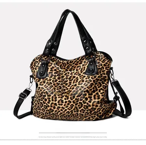 Detail of leopard print tote bag with black leather handles and silver stud accents
