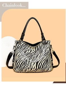 Detail of zebra print tote bag featuring black leather handles and silver hardware