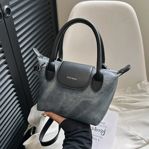 Sac seau en denim bleu avec poignées en cuir noir et détails métalliques argentés