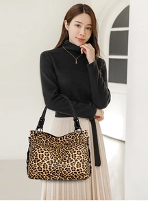 Close-up of stylish leopard print handbag with sleek black handles worn by a model