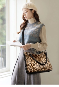 Close-up of leopard print tote bag with black leather straps and metal chain detail
