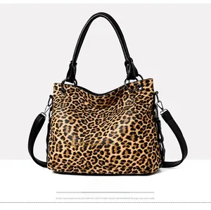 Detailed close-up of leopard print tote bag featuring black leather handles and metal hardware
